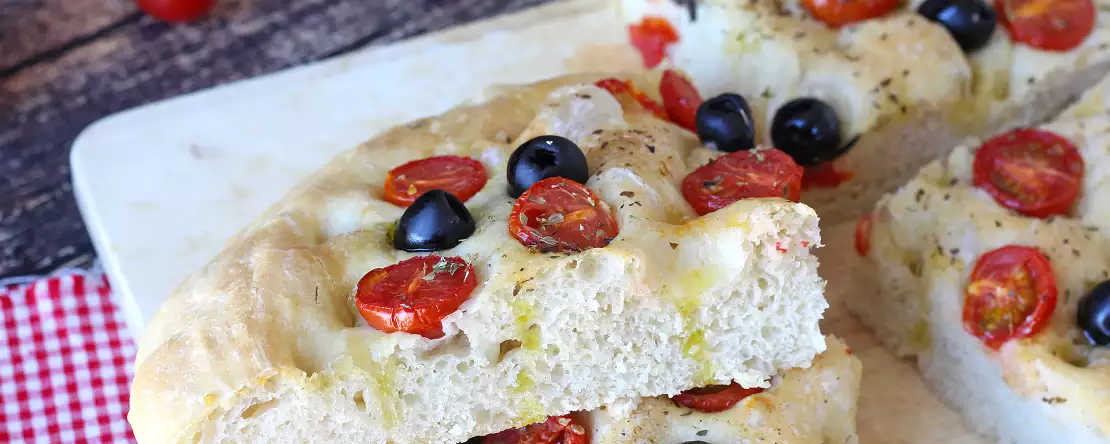 Ta gruba focaccia z pomidorkami koktajlowymi i oliwkami urzeka już samym zapachem: przepis, który warto wypróbować